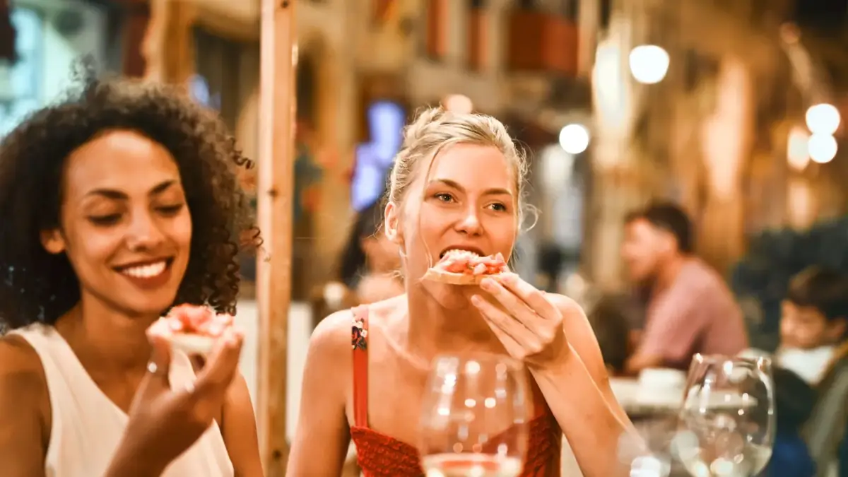 Friends eating bruschetta with wine at an evening restaurant