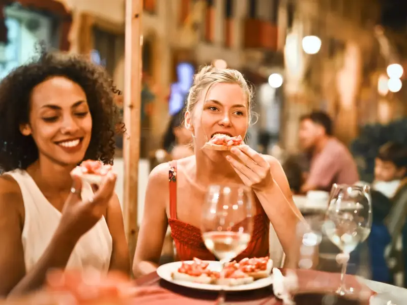 Friends eating bruschetta with wine at an evening restaurant