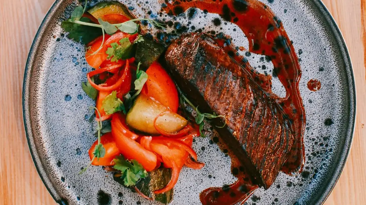 Sliced grilled steak with roasted vegetables and sauce