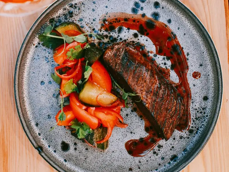 Sliced grilled steak with roasted vegetables and sauce