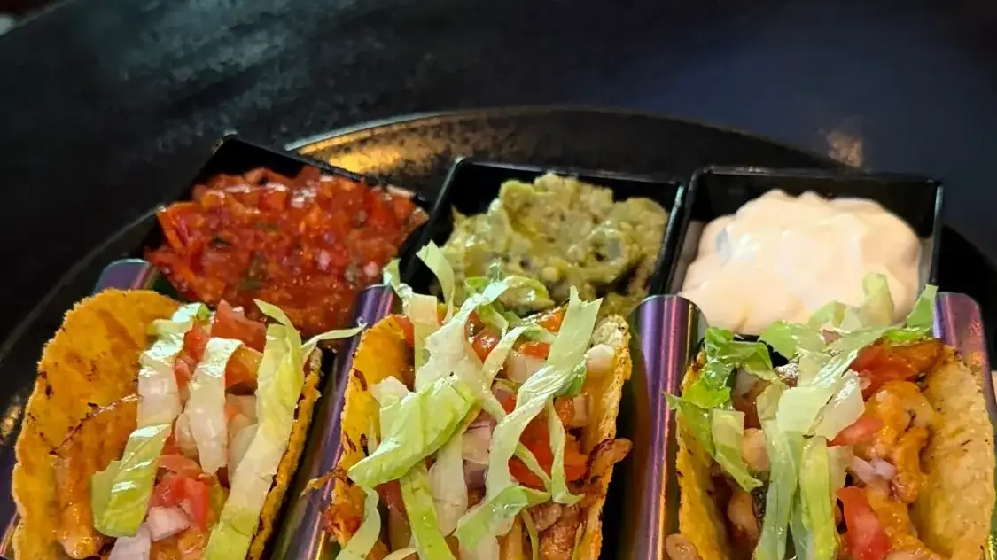 Three chicken tacos with salsa, guacamole and sour cream