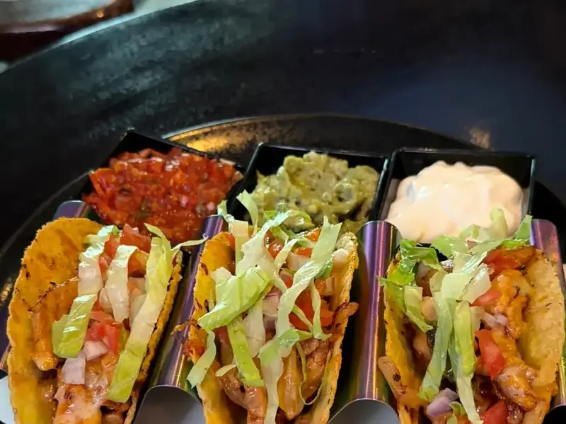 Three chicken tacos with salsa, guacamole and sour cream